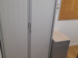 a closet in the corner of a room with a desk and a chair