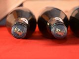 three bottles of wine are lined up on a red cloth