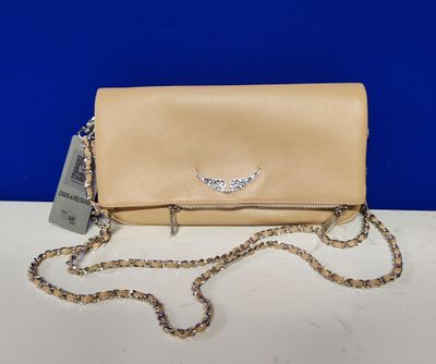 a beige clutch bag with a chain strap on a white table
