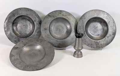 trois assiettes en argent et un bougeoir en argent posés sur une surface blanche