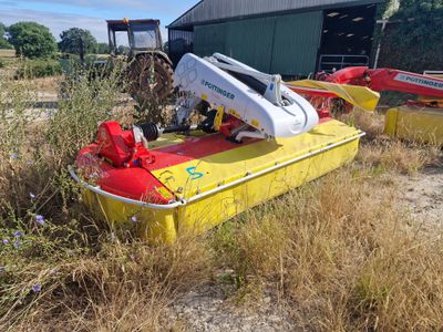 un bateau jaune et rouge dans l'herbe, près d'un bâtiment