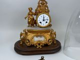 a gold clock sitting on top of a wooden table