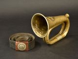 a brass horn and a leather belt on a black background