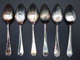 six spoons are lined up in a row on a black surface