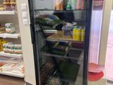 un réfrigérateur à porte vitrée dans un magasin rempli de produits alimentaires