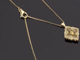 un collier en or avec un pendentif en forme de fleur et une chaîne sur un fond noir