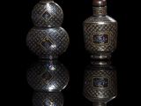 two silver vases sitting next to each other on a black surface
