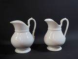 two white pitchers sitting next to each other on a table