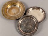 three silver plated dishes on a gray surface with one silver plate in the middle