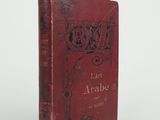 an old book with a red cover sitting on top of a table