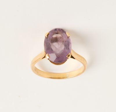 une bague en or jaune sertie d'une pierre violette