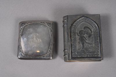 two antique silver cigarette cases sitting on top of a white table