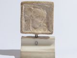sculpture représentant une femme, posée sur un bloc de pierre reposant sur un socle en bois