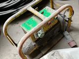 un petit générateur portable posé par terre à côté d'un tas de tuyaux
