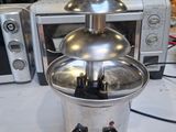 a silver chocolate fountain sitting on a table next to a microwave