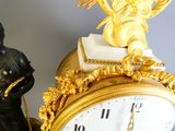 a clock with a statue on top of it next to a statue of an angel