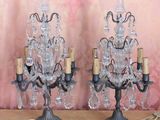 two crystal chandeliers on a table with a pink wall in the background