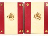 two red and white books with gold trims and a bird on the cover