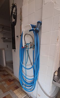 a blue hose attached to a wall next to a toilet