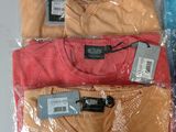three men ' s t - shirts wrapped in plastic on a table