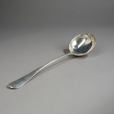 cuillère en argent à long manche posée sur une surface grise