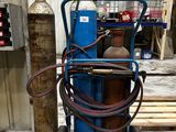 un chariot bleu sur lequel se trouvent un bidon d'essence et un tuyau