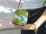 a woman that is holding a small mirror in her hand