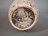 a white vase with black spots on it on a gray surface