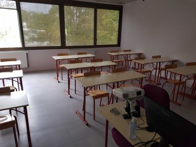 many desks and chairs in this classroom with a computer on the desk