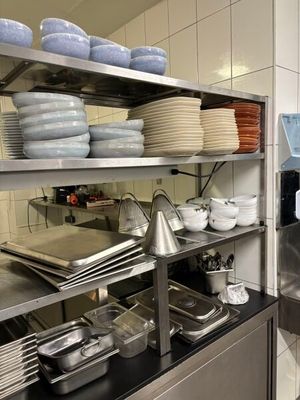 many plates and pans on the shelves in the kitchen