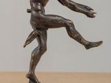 statue en bronze représentant un danseur, posée sur un socle posé à son tour sur une table en bois