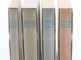 quatre livres sont alignés sur une surface blanche