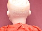 a small doll that is sitting on a pink surface