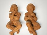 two carved figurines of a man and a woman sitting on their knees
