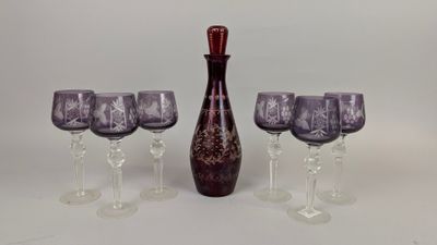 four wine glasses and a wine decanter on the table