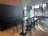 tables and stools in a restaurant with a large window in the background