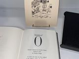 an open book sitting on top of a white table next to a black book