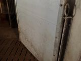 a white refrigerator sitting in a dirty room next to a radiator