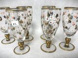 quatre verres à pied ornés d'une bordure dorée et de motifs floraux