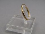 a gold ring on a clear stand on a table