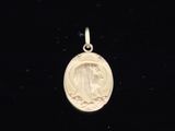 une petite médaille en or représentant une femme de profil sur fond noir