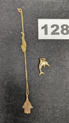 un gros plan sur un collier en or orné d'un dauphin et d'un poisson
