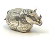 une figurine de rhinocéros posée sur une surface blanche