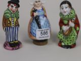 three miniature figurines of people dressed in costumes and hats