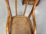 a wooden chair with a wicker seat and a mirror on the wall