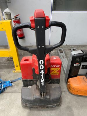 a red and black fork lifter sitting on the ground