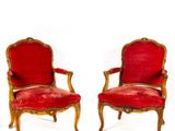 deux chaises rouges ornées de passementerie dorée et dotées d'une assise rembourrée rouge
