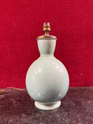 a green vase sitting on a table with a red wall in the background