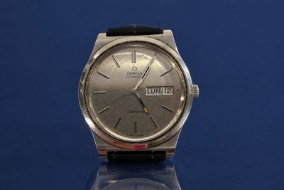 a silver watch with a black strap on a blue surface