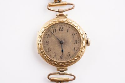 une montre en or entourée d'une chaîne sur une surface blanche